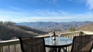 - une table avec deux verres de vin sur le balcon dans l'établissement Blue Ridge Mountain Air Retreat with epic mountain views!, à Burnsville