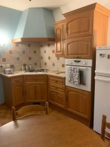 uma cozinha com armários de madeira e um frigorífico branco em Ancient Mill with Beautiful Lake and Streams em Les Riffes