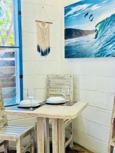 a table with two wine glasses and a painting on the wall at La Bocana Beach House in Santa Maria Huatulco