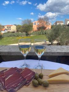 zwei Gläser Wein auf einem Tisch mit Fleisch und Oliven in der Unterkunft Villa Ignoto in Bale