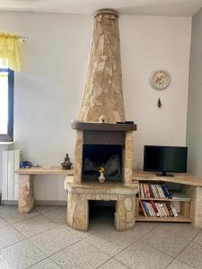 Villa Ignoto في بال: مدفأة حجرية في غرفة معيشة مع تلفزيون