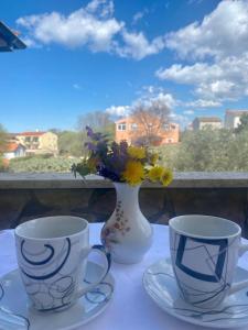 two cups and a vase with flowers on a table at Villa Ignoto in Bale