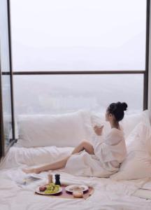 Bohr Apartment Copenhagen في كوبنهاغن: امرأة جالسة على سرير مع صينية من الطعام