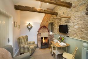 sala de estar con chimenea, mesa y sillas en Bramwood Cottages, en Pickering