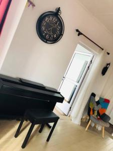 een kamer met een piano en een klok aan de muur bij Chez Moi in Chemin Grenier