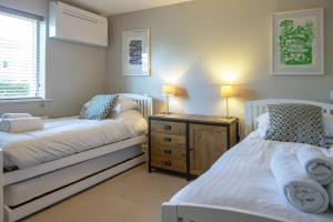 a bedroom with two beds and a dresser and a window at Clearwater 31, The Lakehouse in Somerford Keynes +28 photos