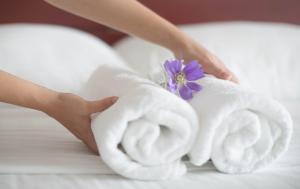 a woman with two towels on a bed with a purple flower at Apartment Erika in Oberasbach