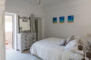 um quarto com uma cama e uma cómoda com um espelho em The Beach House em Vila Nova de Cacela