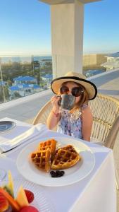 a little girl sitting at a table with a plate of waffles at Margaritaville Island Reserve Cap Cana Wave - An All-Inclusive Experience for All in Punta Cana