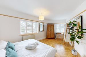 um quarto com uma cama branca e uma planta em Stunning 2 bed flat in Richmond em Kew