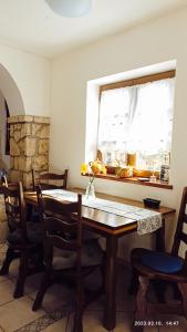 a dining room table with chairs and a window at Almáskert Vendégház in Mónosbél