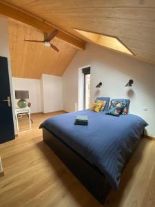 a bedroom with a large blue bed with a wooden ceiling at Le Pied du Loup - Maison de village clunisois au calme 6-7 personnes in Flagy