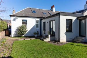 una casa blanca con un césped verde delante de ella en Briarhill - Donnini Apartments, en Prestwick