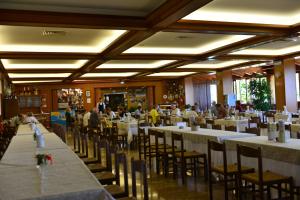 ein Restaurant mit weißen Tischen und Stühlen und Menschen essen in der Unterkunft Hotel Miramonti in Sestola