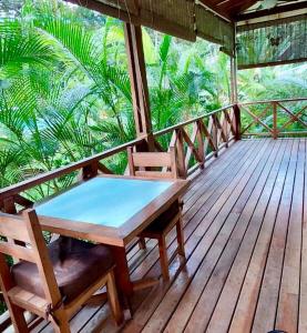 a wooden porch with a table and two chairs on it at Peace Garden Spacious Bungalows- a walk to the beach in Cocles