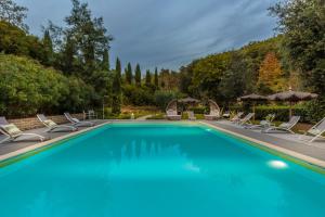 a swimming pool with lounge chairs and umbrellas at Villa Veranda, a Romantic Farmhouse with Pool in Larciano