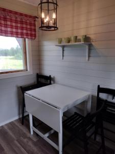une salle à manger avec une table blanche et deux chaises dans l'établissement Piilijärvi Camping, à Gällivare