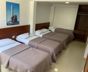 a row of beds in a room with a tower at Hotel El Faro Buga in Buga