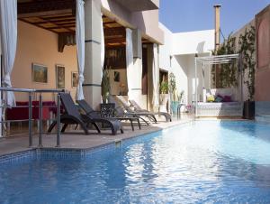 Hotel Lawrence d'Arabie في مراكش: مسبح في فندق يوجد كراسي بجواره