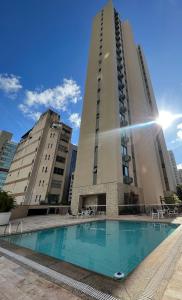 a tall building with a swimming pool in front of it at Locking's Funcionários 6 in Belo Horizonte