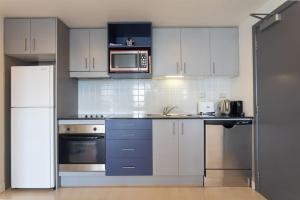 a kitchen with white cabinets and a microwave at Stunning Light-filled 2Bed w Car Park in Auckland