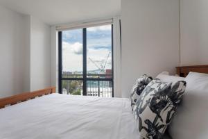 a bedroom with a bed and a large window at Stunning Light-filled 2Bed w Car Park in Auckland