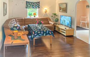a living room with a couch and a tv at Beautiful Home In Hstveda With 3 Bedrooms in Askustorp