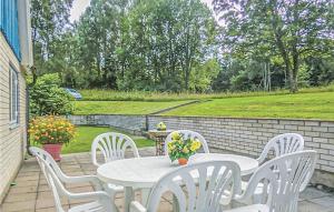 a patio with white chairs and a table with flowers at Beautiful Home In Hästveda With Kitchen in Askustorp