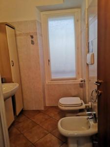 ein Bad mit einem WC, einem Waschbecken und einem Fenster in der Unterkunft Casa vacanze il Tuffetto in Olginate