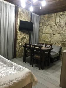 1 dormitorio con mesa, sillas y TV en David guest house LOFT Коттеджи на берегу реки, en Dilijan