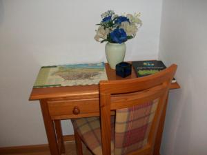 una pequeña mesa de madera con un jarrón de flores. en Pension Paseo Real, en Cangas de Onís