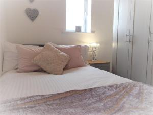 1 cama con almohadas rosas y blancas y ventana en Sea View Apartment Blyth, en Blythe