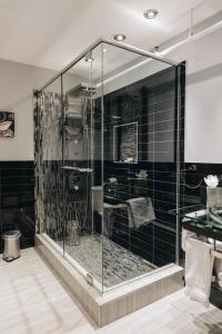 a glass shower in a bathroom with black tiles at Lofts du Vieux-Port by Gray Collection in Montréal