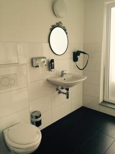 a bathroom with a toilet and a sink and a mirror at Hotel Cara Vita Cologne in Cologne