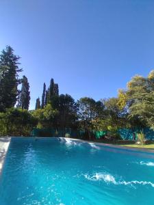 una piscina de agua azul con árboles en el fondo en Cabaña Los Hornillos Mínimo 2 noches en Los Hornillos