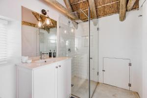 a white bathroom with a shower and a sink at Bliss on the Bay in Struisbaai