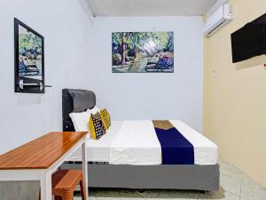 a small bedroom with a bed and a desk at SPOT ON 92319 White House Syariah in Yogyakarta