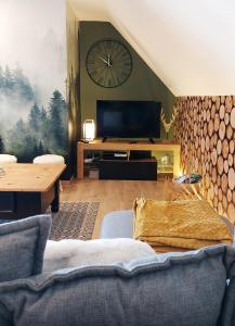 een woonkamer met een grote klok aan de muur bij La forêt des Marmottes in Besse-et-Saint-Anastaise