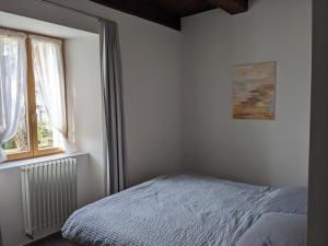 a white bedroom with a bed and a window at Casa Ai Portici in Gordola