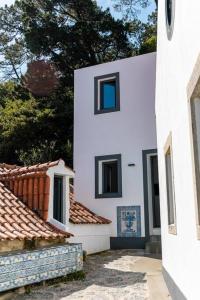 um edifício branco com duas janelas e alguns telhados em Casinha - Lusitália Eden em Sintra