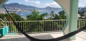 a hammock on a balcony with a view of the water at Casa Costa Brava in Acapulco