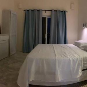 a bedroom with a white bed and blue curtains at Piscina vista al mar, Jacuzzi con agua caliente in Río San Juan