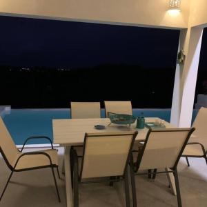 a dining room table and chairs with a view of the city at Piscina vista al mar, Jacuzzi con agua caliente in Río San Juan