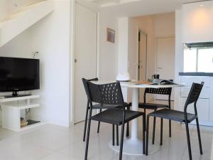 jadalnia ze stołem i krzesłami oraz telewizorem w obiekcie Duplex moderne 5 pers avec terrasse et parking - FR-1-251-456 w mieście Le Lavandou