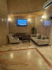 a living room with couches and a tv on a wall at فندق شموخ السعد in Mecca