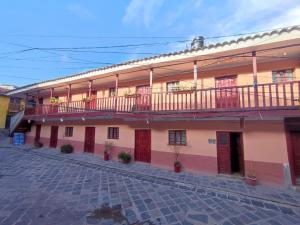 a large building with red doors and a balcony at Anais y Nicolas Hostel in Cusco