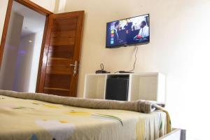 a room with a tv on the wall and a bed at DALOU Chambre hôte, Cité mixta in Dakar