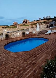 a large swimming pool on a wooden deck at Pamela's house "private pool and spa" in Karteros