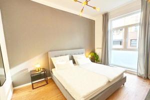 - une chambre avec un lit blanc et une grande fenêtre dans l'établissement 80qm Apartment in Krefeld zentral gelegen mit hohen Decken - BEUYS Apartments - Krefeld, à Krefeld