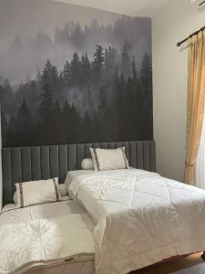 ein Schlafzimmer mit einem Bett und einem Waldbild in der Unterkunft Apple eight 2BR Villa in Batu